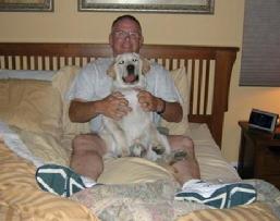 Tom Kunick having a dog while sitting on the bed